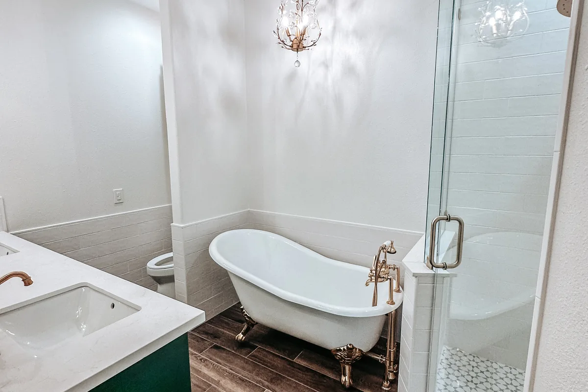 Remodeled bathroom with a clawfoot tub, glass walk-in shower and green vanity in Pearland, TX
